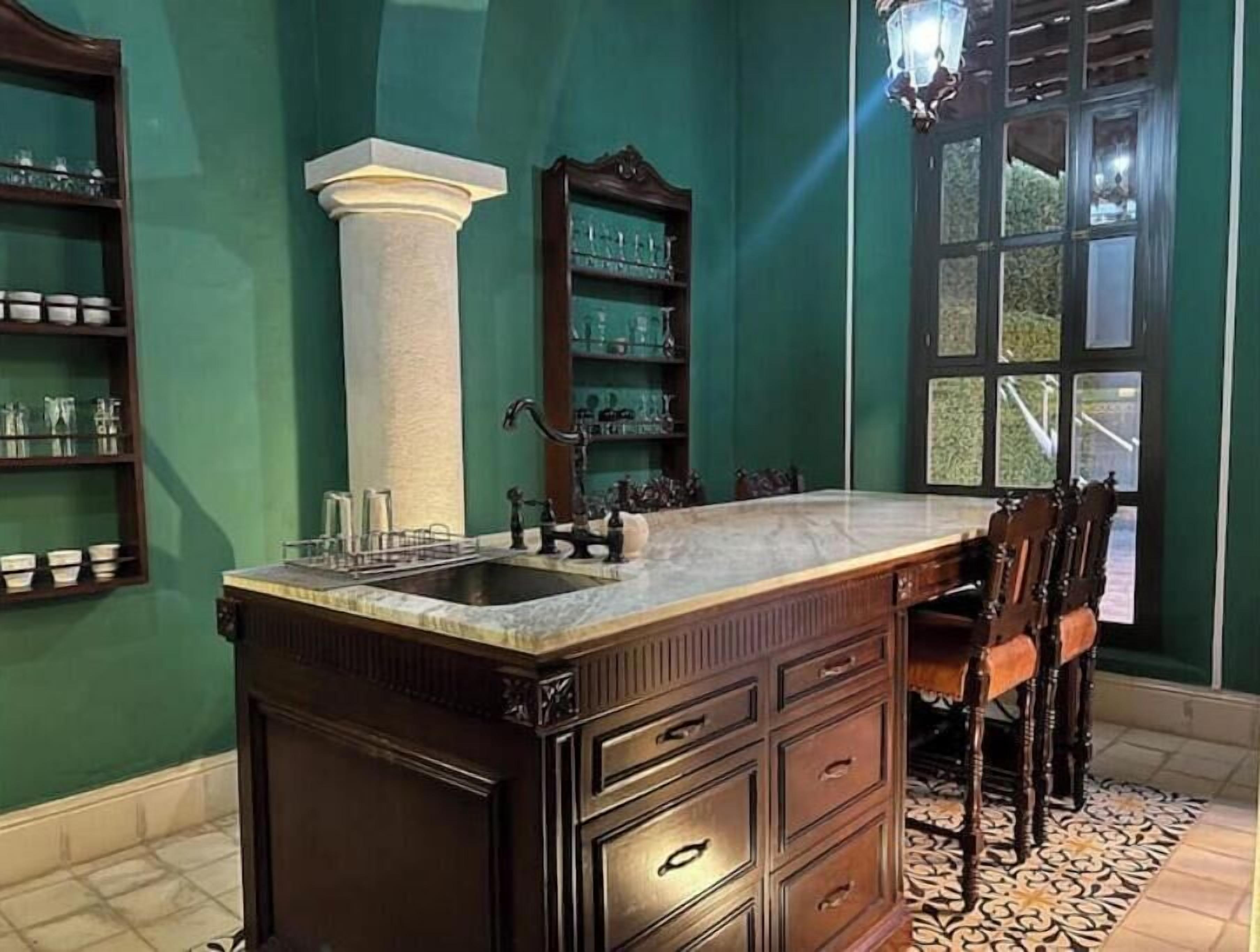 A kitchen with a marble countertop, dark wooden cabinets, and a large window.