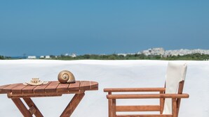 A wooden table with a shell and a plate, a wooden chair, and a white surface against a clear blue sky. - My Villa, 2-bedroom villa in gorgeous Naxos with AC, WiFi (Naxos)