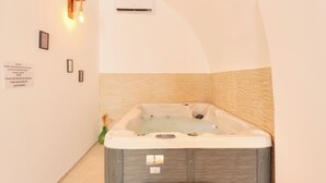 Um quarto de spa com hidromassagem, unidade de ar condicionado na parede e placas informativas emolduradas.