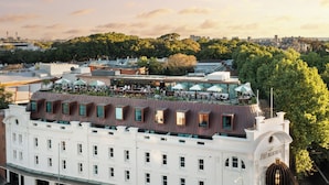 Un hotel con terraza en la azotea, mobiliario exterior y jardín.