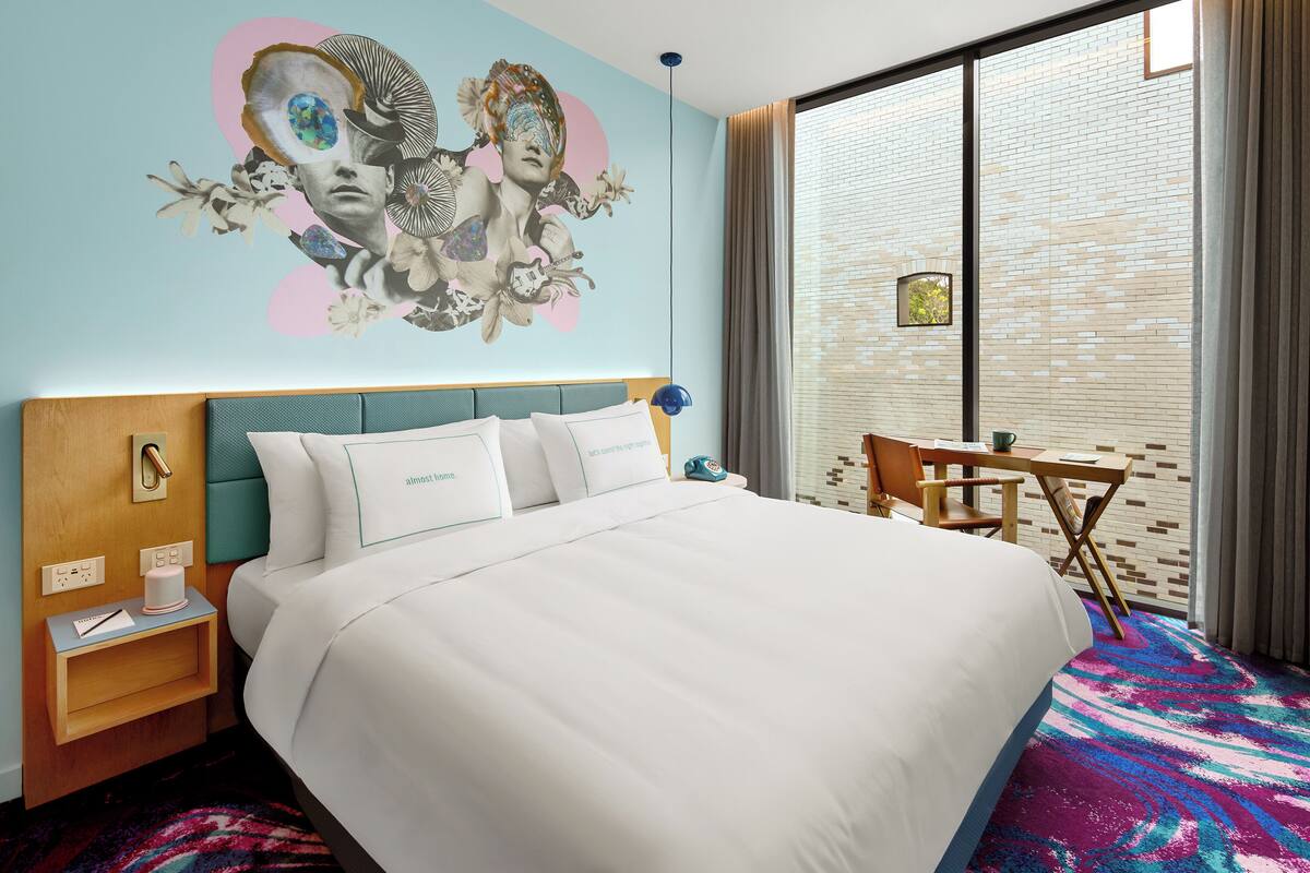Hotelkamer met een groot bed, een bureau en een raam met uitzicht op de stad.