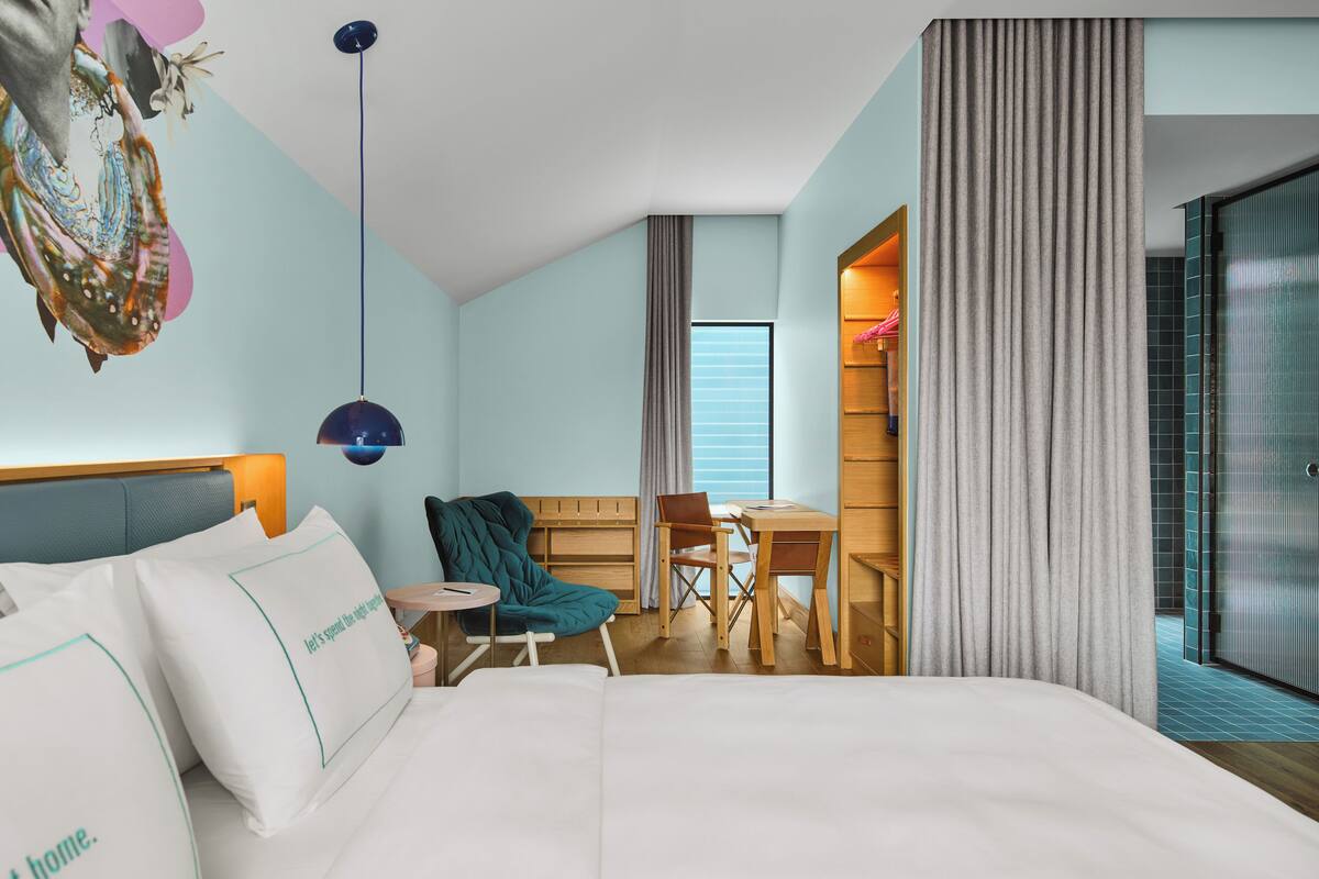 Een hotelkamer met een bed, een bureau, een stoel en een groot raam.