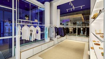 A modern retail space with clothing displays and a visible store named 'Monica'.