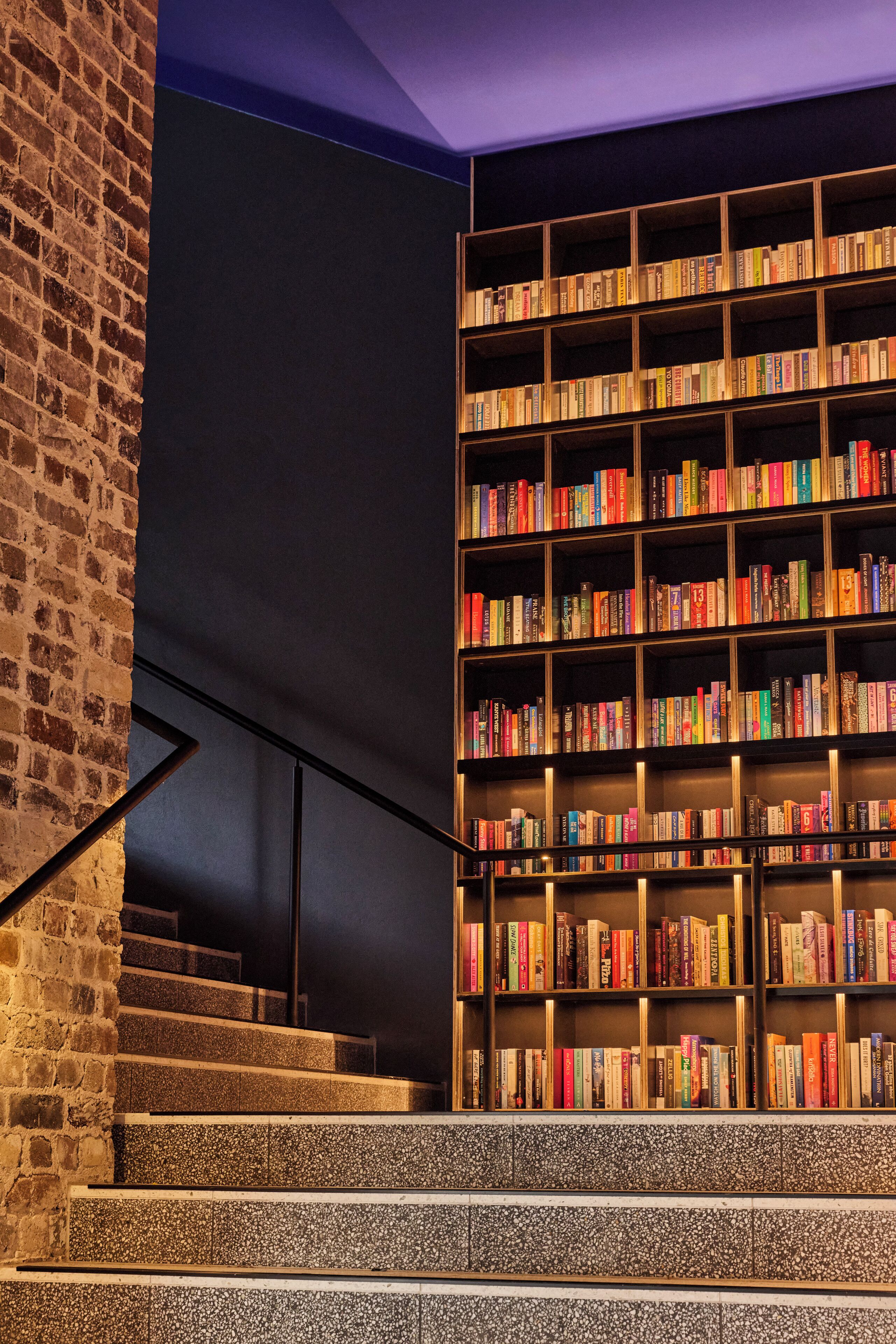 Uma escada leva a uma estante em vários níveis, repleta de livros.
