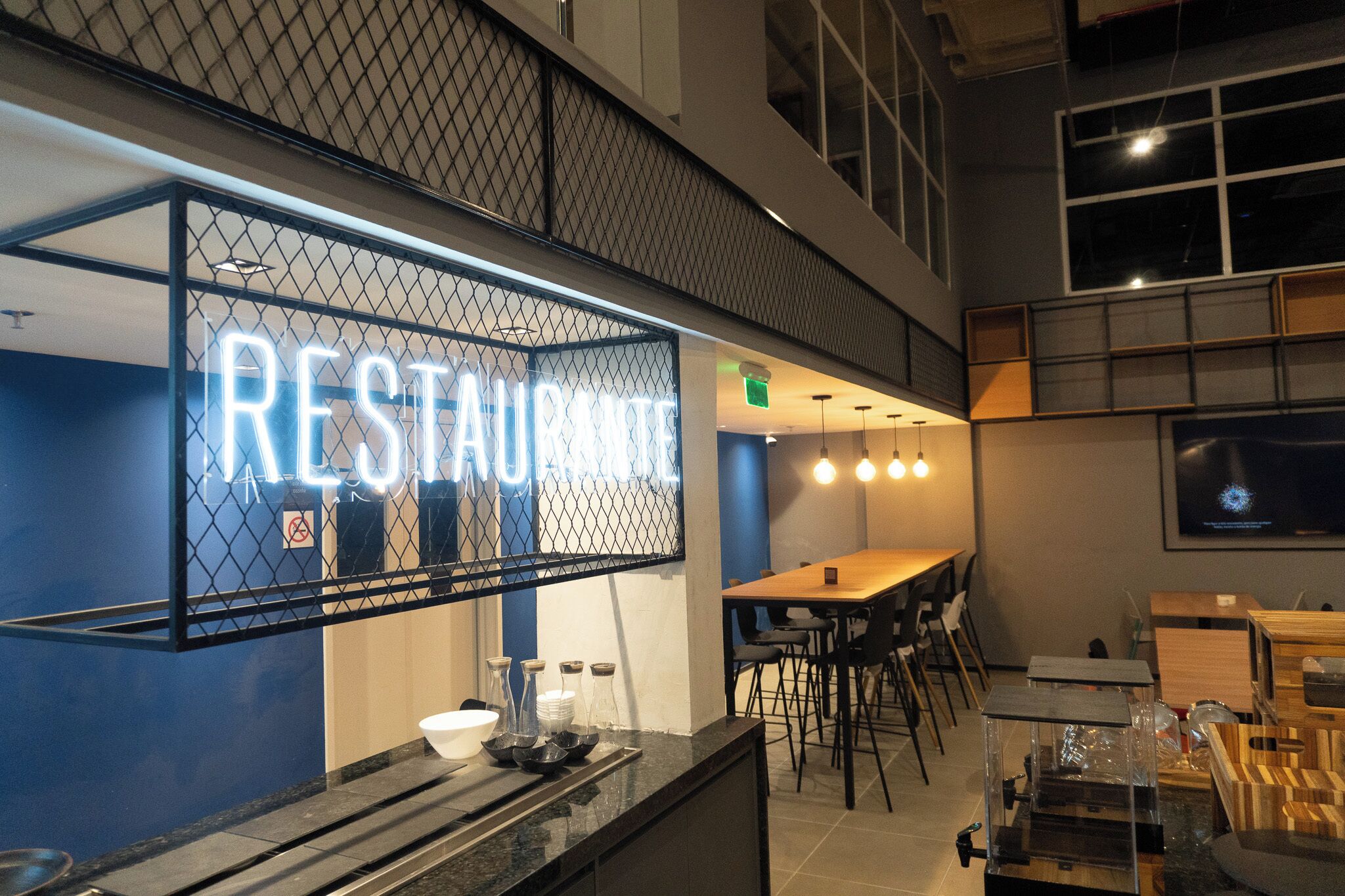 A restaurant with a neon sign, a bar area, and a seating arrangement.