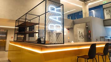A modern bar area with a neon sign, seating, and a counter.