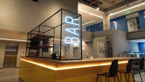 Eine moderne Bar mit Neonreklame, einer Rezeption und Sitzgelegenheiten.