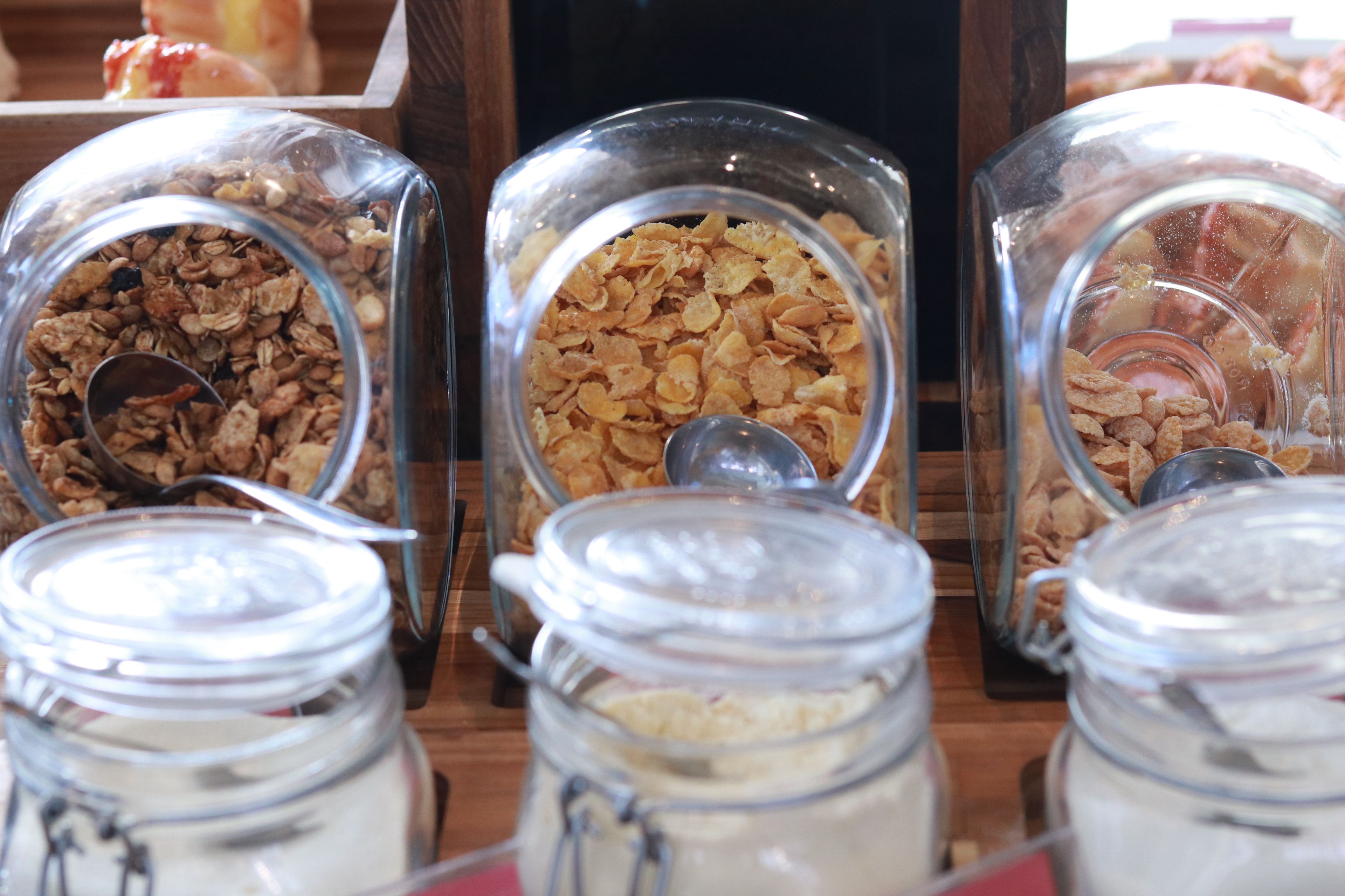 Three glass jars with metal lids, each containing different types of cereal.