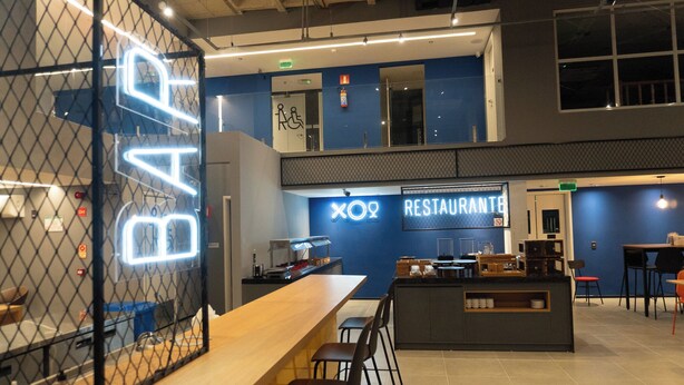 Eine moderne Bar mit einer Neonreklame, einer Theke und Sitzplätzen.