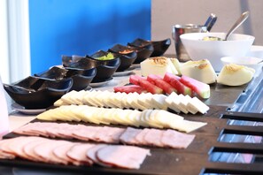 A buffet with various food items including sliced meats, fruits, and desserts.