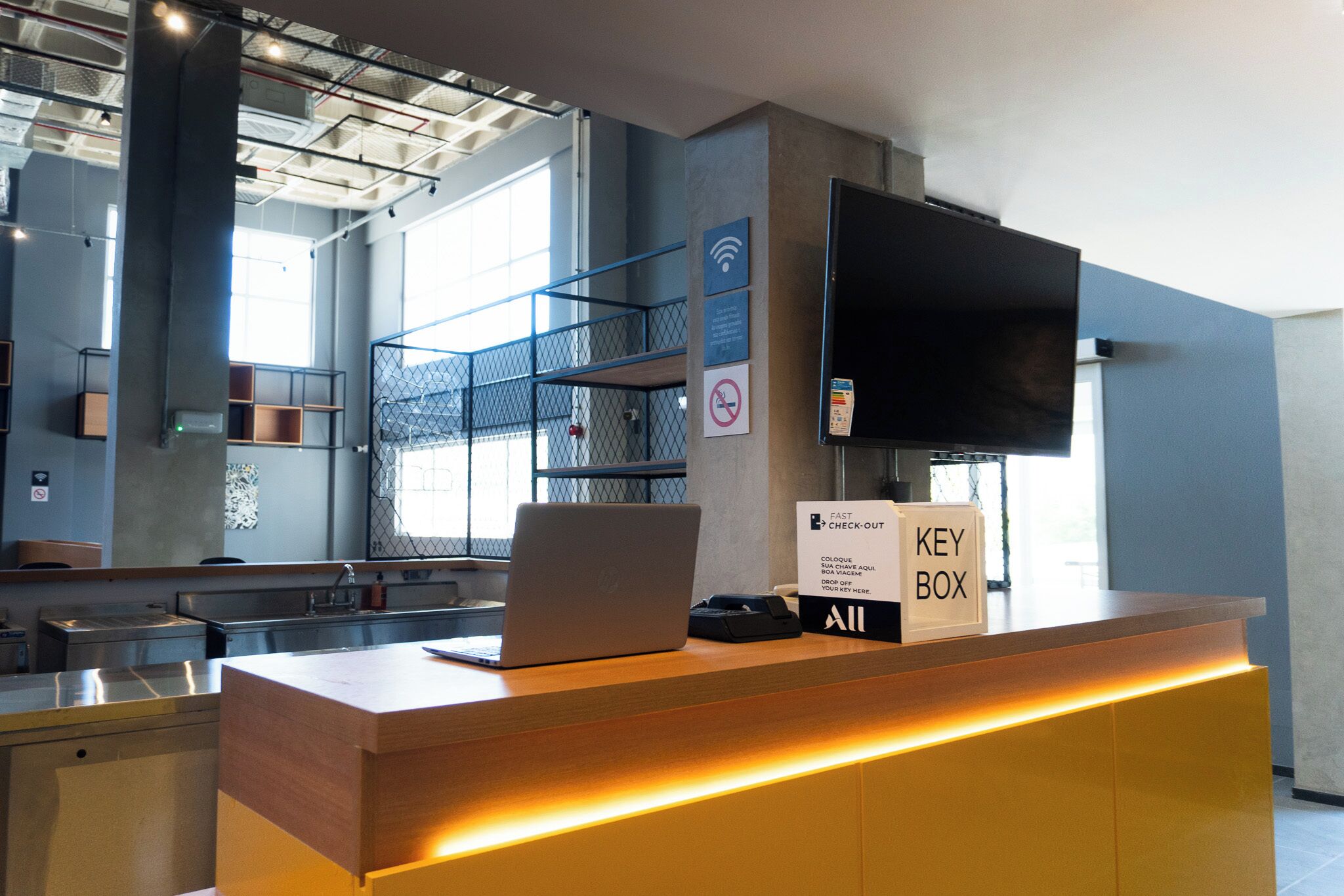 A hotel reception desk with a laptop, a key box, and a sign indicating a fast check-out service.
