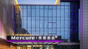 A modern hotel entrance with a glass facade, a neon sign, and a covered entrance area.