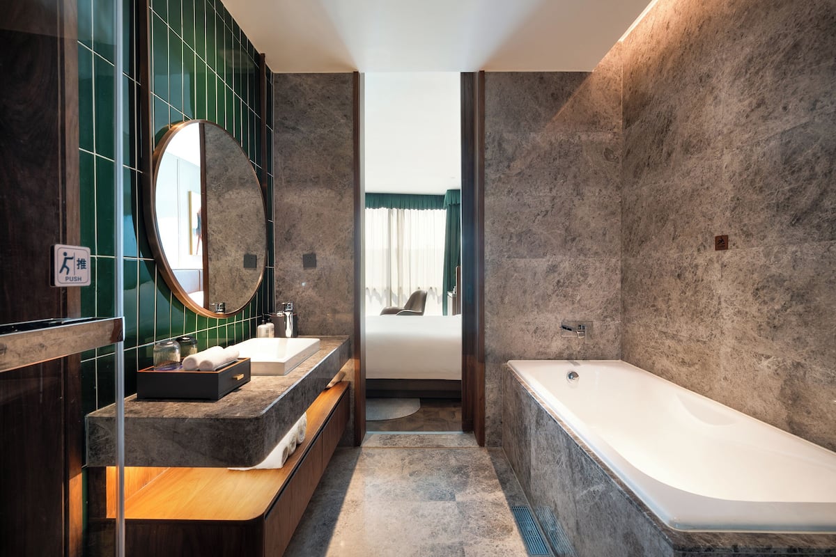 A modern bathroom with a large mirror, a bathtub, and a vanity with a sink.