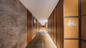 Pasillo de hotel con piso estampado, paneles de madera y un letrero que indica la habitación 1107.