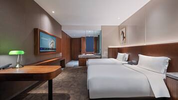 Una habitación de hotel con una cama grande, un escritorio con lámpara, un televisor montado en la pared y un baño visible a través de una puerta abierta.