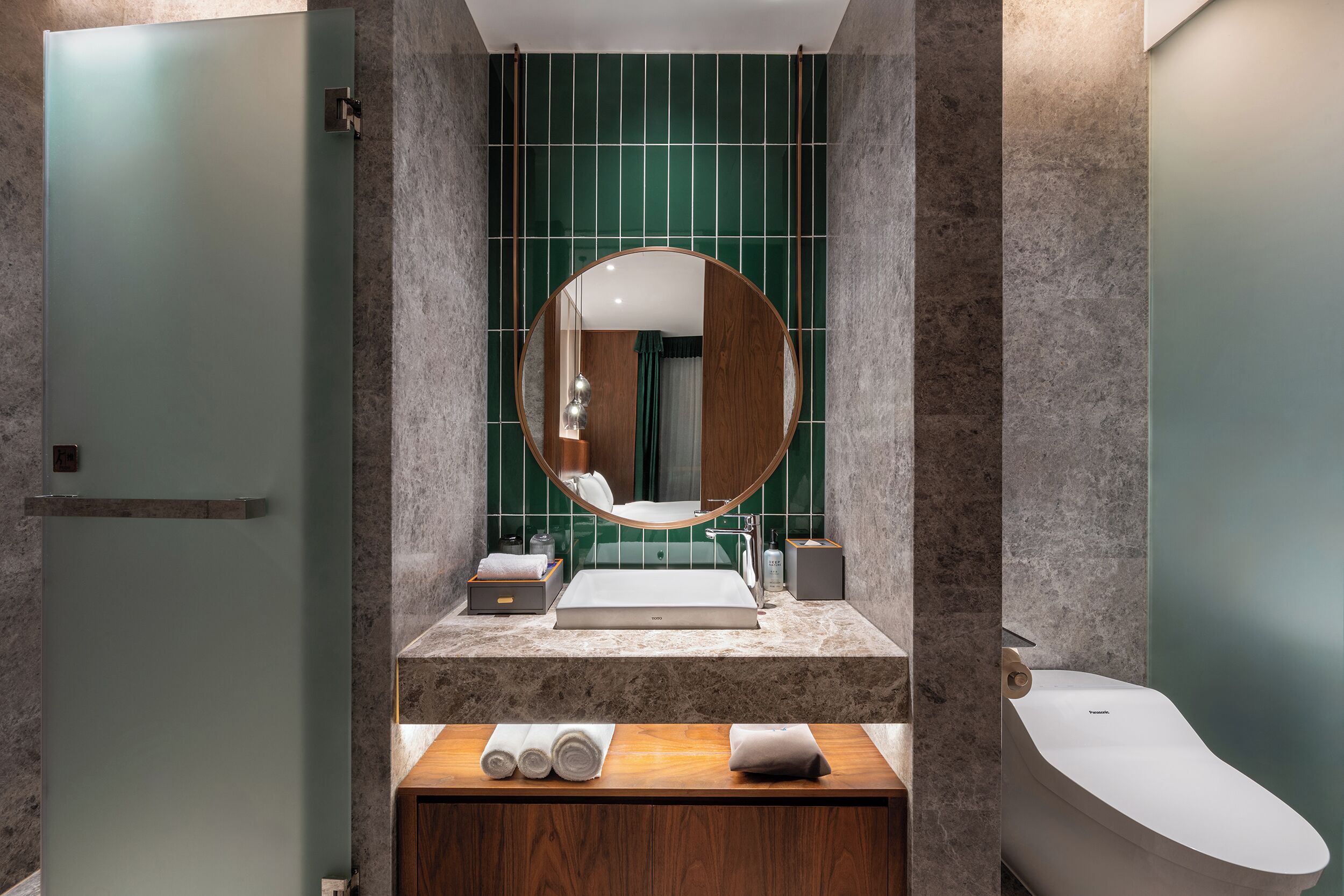 Ein modernes Badezimmer mit einer freistehenden Badewanne, einem runden Spiegel, einem Waschbecken und einem Waschtisch mit Handtüchern.