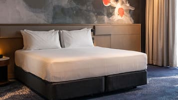Habitación de hotel con una cama grande, un cabecero con diseño texturizado, una mesita de noche con lámpara y un mural en la pared con carpas.