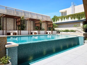A swimming pool with a tiled edge, stone walls, and a pergola structure. - Novotel Sydney Cabramatta (Canley Vale)