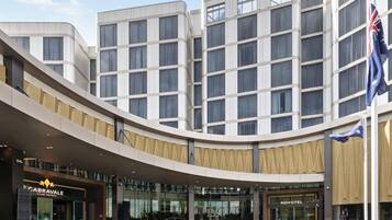 Un hôtel moderne à plusieurs étages, doté d’une entrée imposante et d’un mât sur lequel flottent des drapeaux.
