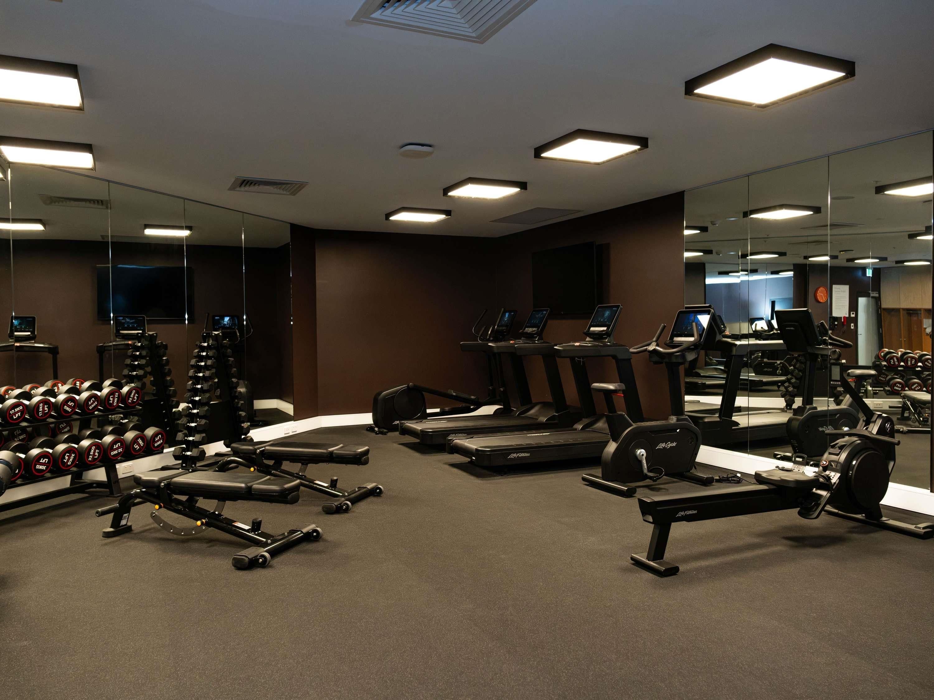 Ein Fitnessstudio mit Laufbändern, Kurzhanteln und Kraftgeräten.