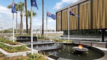 Een modern gebouw met Australische vlaggen, een waterpartij met vuurkorf en aangelegde tuinen.