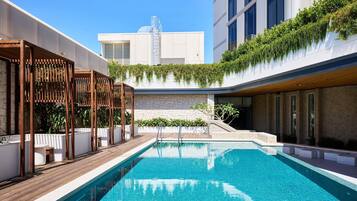 Alberca al aire libre, sombrillas en la alberca y camastros