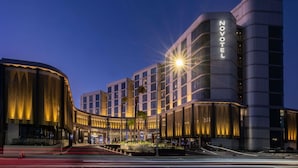 A modern hotel with a prominent 'NOVOTEL' sign, featuring a curved facade and a well-lit entrance. - Novotel Sydney Cabramatta (Canley Vale)