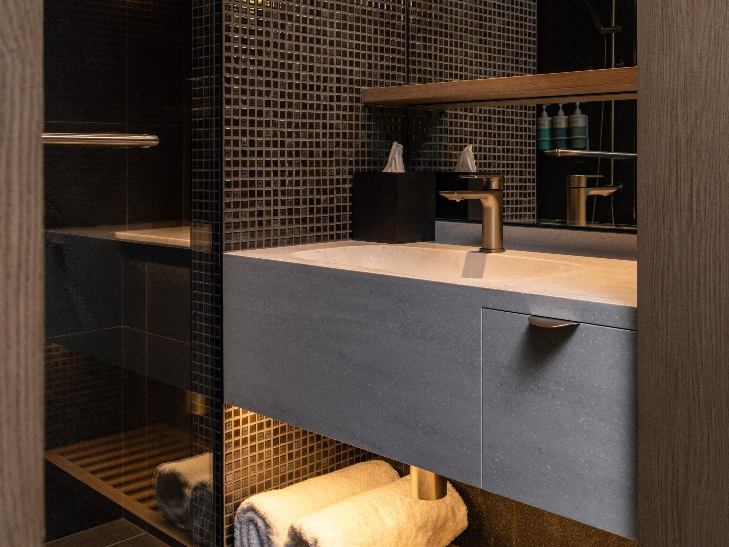 A modern bathroom with a glass shower enclosure, a sink with a faucet, and a towel rack.