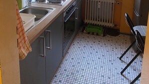 Une cuisine de taille réduite, avec une fenêtre, un radiateur et un évier.