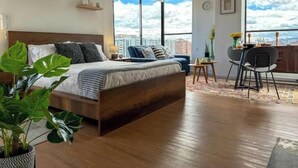 A modern bedroom with a large bed, a city view, and a dining area with a view. - Beautiful Loft in Bogota-Charming View-Gym (Bogotá)