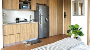 A compact kitchen with wooden cabinets, a stainless steel refrigerator, and a coffee maker on the counter. - Beautiful Loft in Bogota-Charming View-Gym (Bogotá)