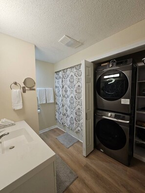 Un baño pequeño con lavamanos, toallero y zona de ducha con cortinas estampadas.