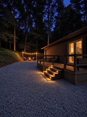 A wooden cabin with a deck and outdoor seating area, surrounded by trees and gravel. - Dual Living Areas 2 Kitchens + 2 Living Rooms Dogs Welcome Near UT (Knoxville)