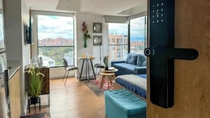 En moderne lejlighed med spiseplads, sofa og et stort vindue med udsigt over byen.