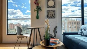 En moderne stue med et stort vindue, en blå sofa, et spisebord og en stol.