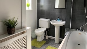 A modern bathroom with a toilet, sink, and bathtub. - Buccleuch Whole Apartment (Kettering)