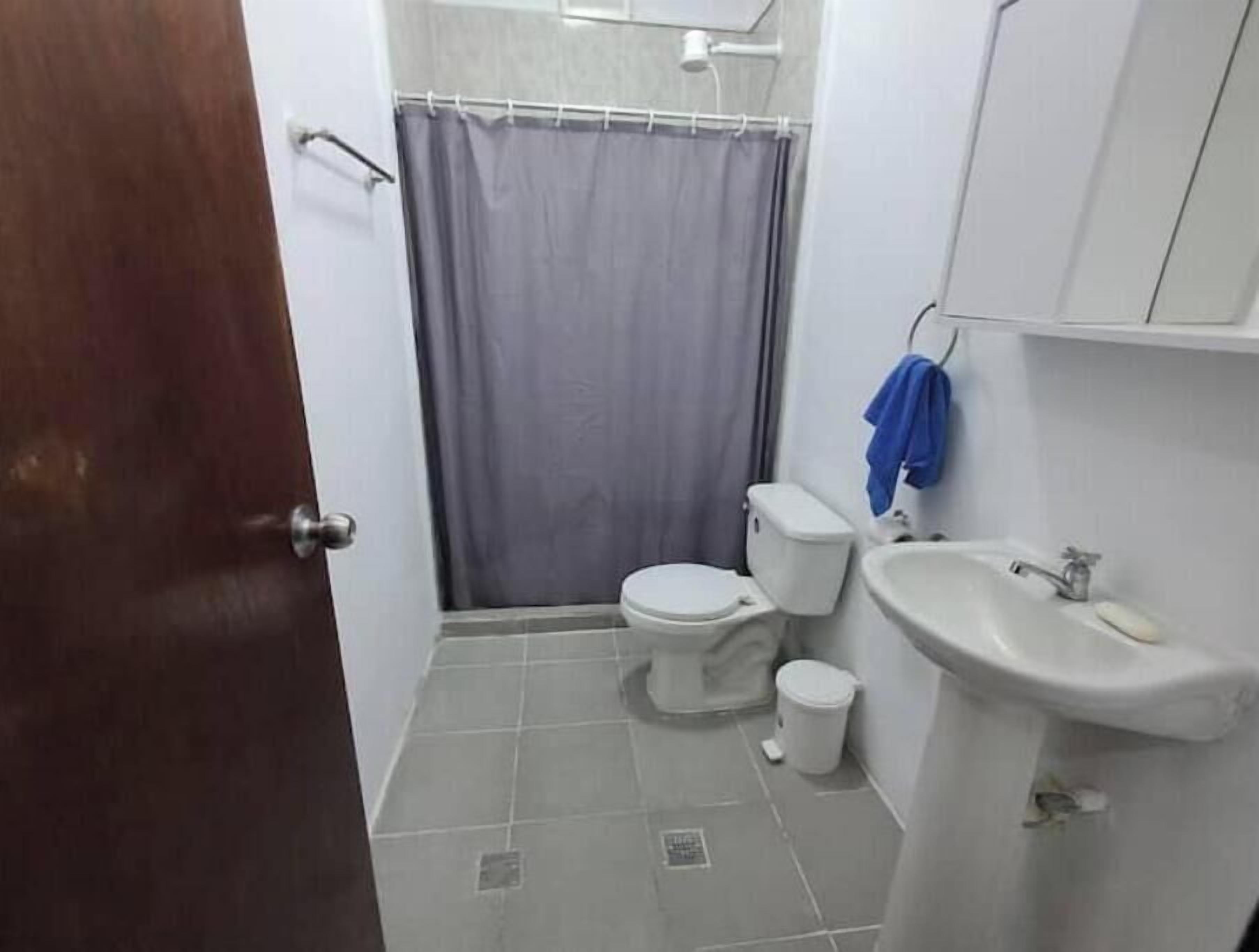 Een kleine badkamer met toilet, wastafel en douchegordijn.