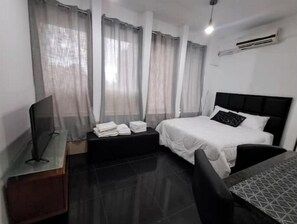 Ein Hotelzimmer mit Bett, Fernseher, Schreibtisch und Stuhl.
