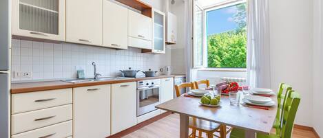 A modern kitchen with white cabinets, a wooden countertop, and a dining area with a table set for four.