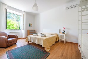 A bedroom with a bed, a chair, a desk, and a window with a view of greenery. - L' Ali Apartment Near Noci old Town (Noci)