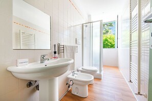 A modern bathroom with a sink, toilet, bidet, and a glass shower enclosure. - L' Ali Apartment Near Noci old Town (Noci)