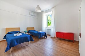 A hotel room with two beds, a red cabinet, and a window with a view of greenery. - L' Ali Apartment Near Noci old Town (Noci)