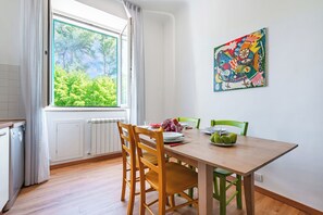 A dining area with a wooden table, chairs, and a window with a view of greenery. - L' Ali Apartment Near Noci old Town (Noci)