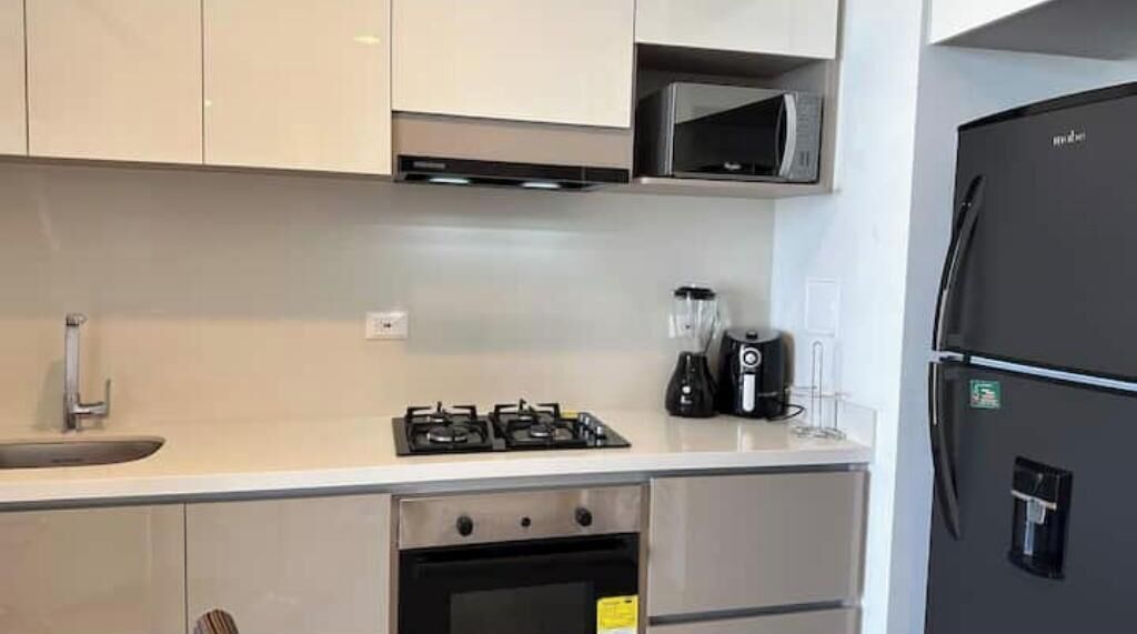 A modern kitchen with a gas stove, oven, microwave, and a black refrigerator.