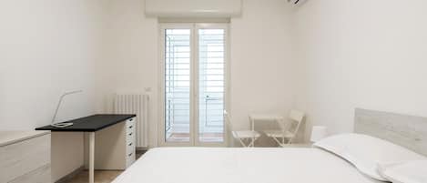 A minimalist bedroom with a bed, a desk, and a chair.