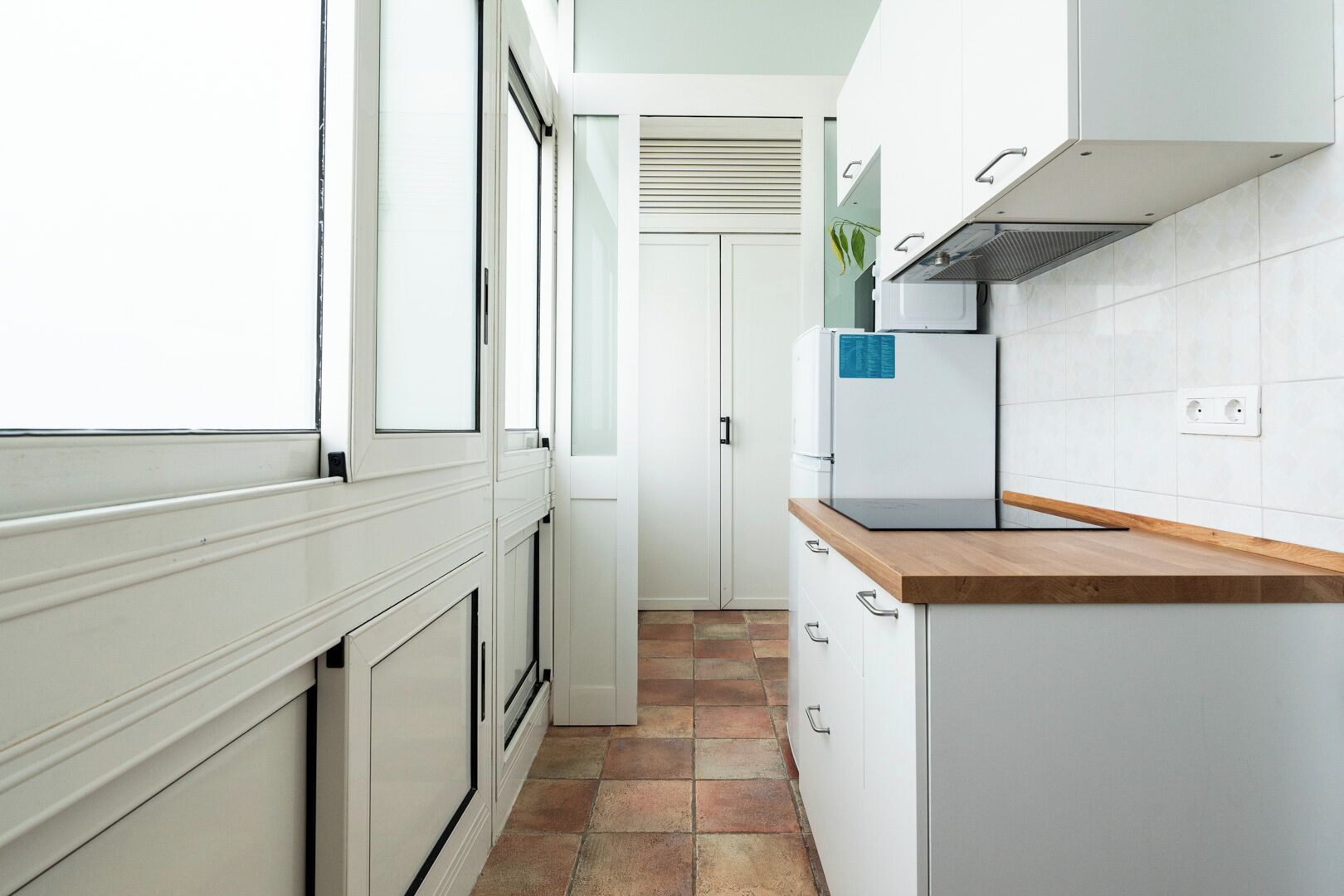 Una cocina moderna con armarios blancos, encimera de madera y estufa empotrada.