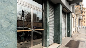 Un bâtiment avec une porte à volets fermés, un vélo garé à l’extérieur et une rambarde en métal.