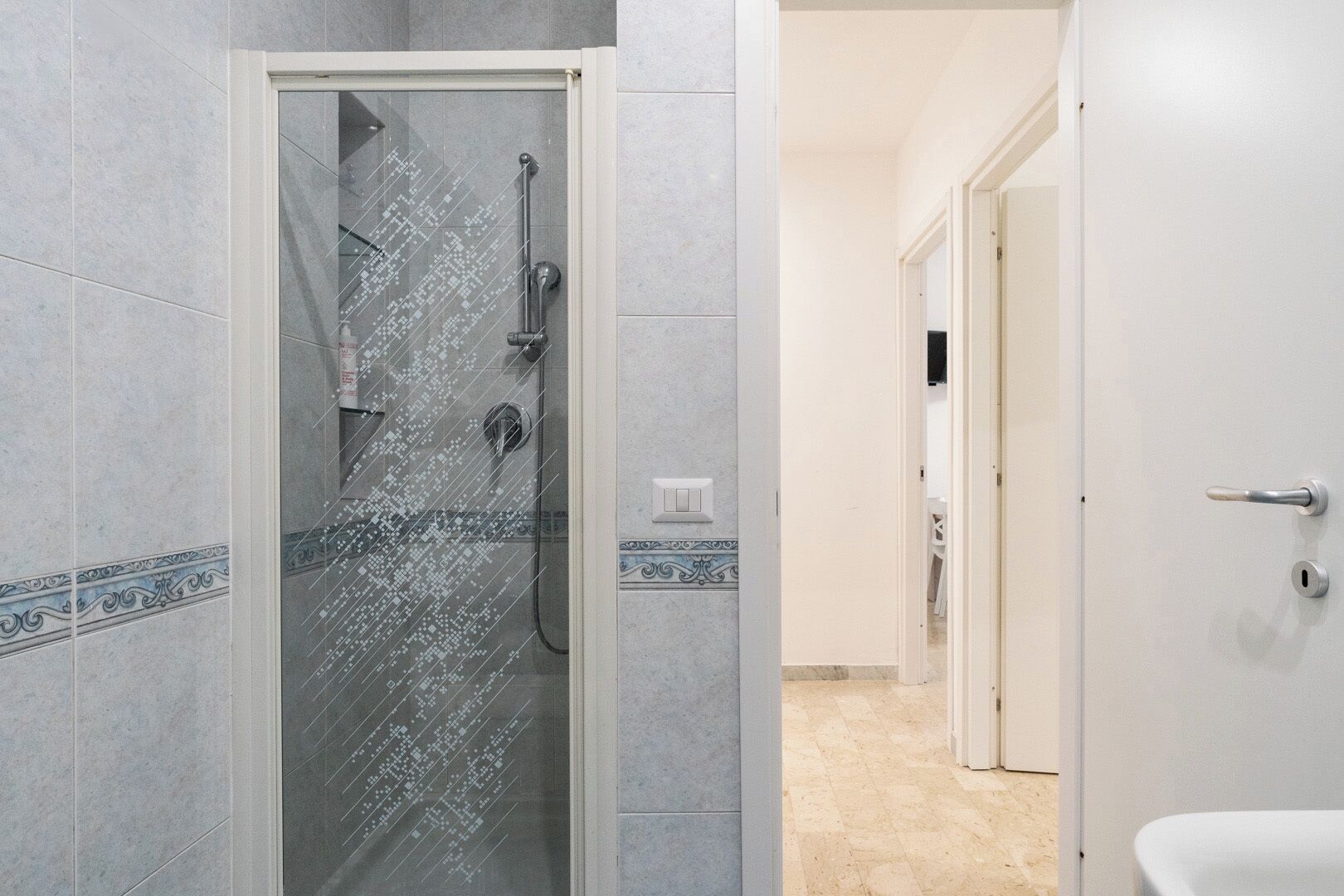 Un baño moderno con ducha de vidrio, inodoro blanco y suelo de baldosas.