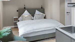 Una camera da letto moderna con un letto, comodini, una lampada a sospensione e un lavabo integrato.