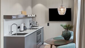 Una cucina moderna con forno integrato, lavello e macchina per il caffè. Un televisore a schermo piatto è montato sulla parete sopra il bancone della cucina.